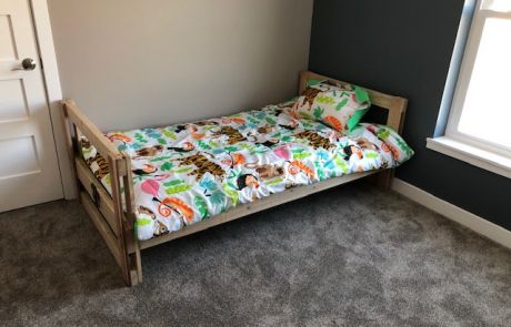 A fully assembled bed donated by Sleep in Heavenly Peace, with sheets, blanket, pillow, and comforter.